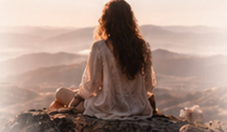 Femme assise sur un rocher face aux montagnes